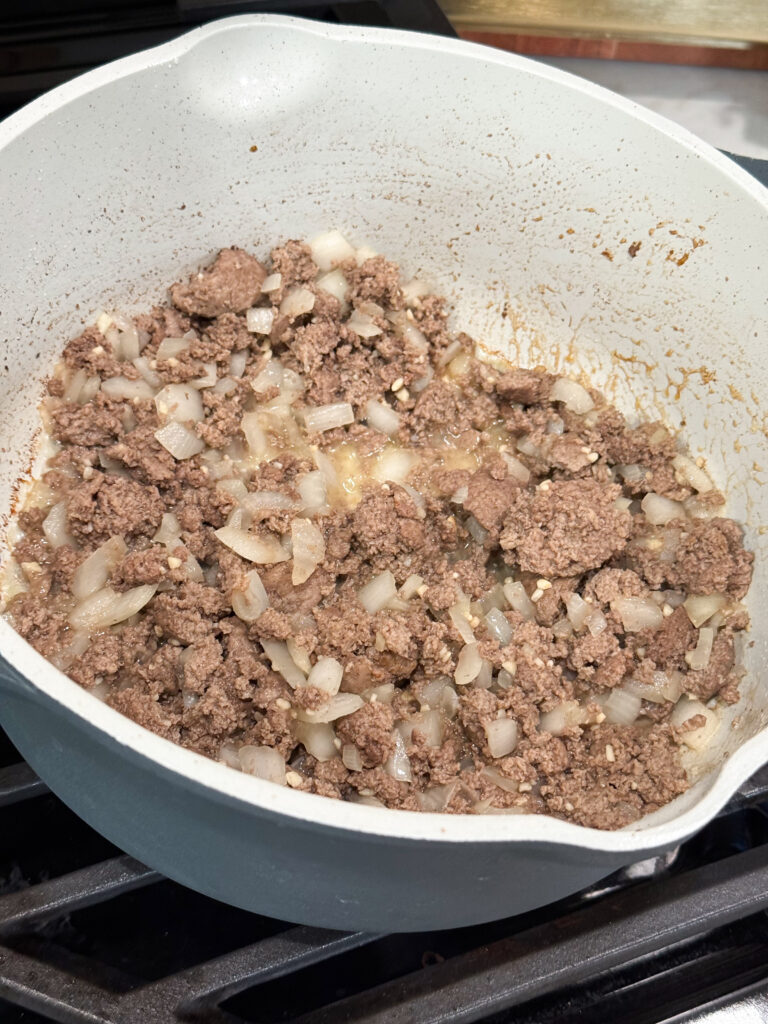 Browned meat and onions in a large skillet on the stovetop