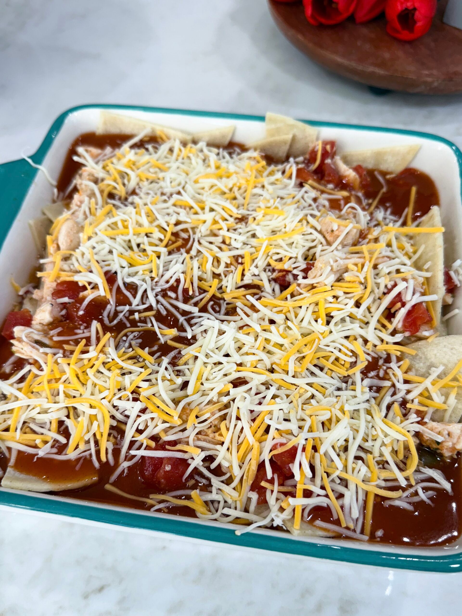 red chili enchiladas in the dish ready to be put into the oven