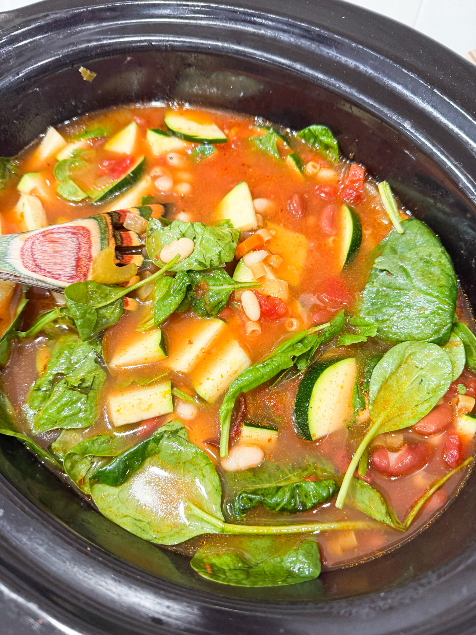 Stirring pasta and spinach into slow cooker soup