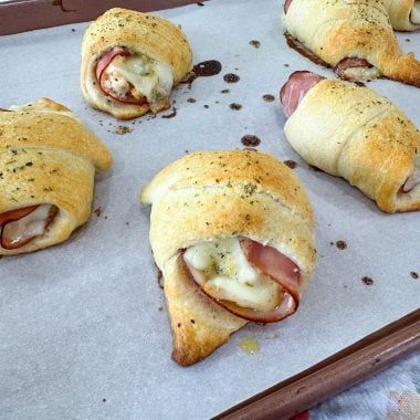 Chicken cordon bleu pockets on baking sheet with golden crust and melted cheese