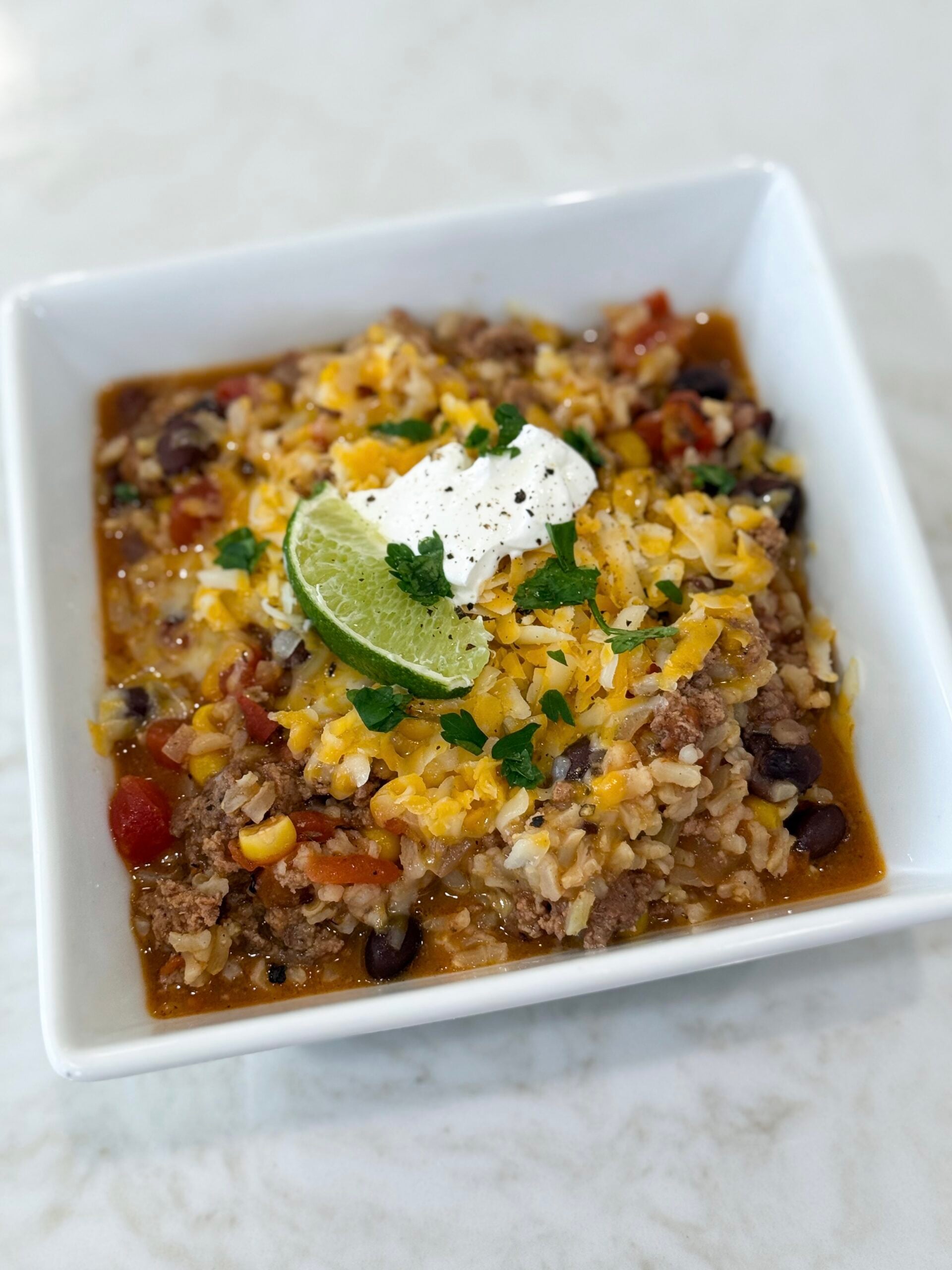 Mexican beef and rice one pot meal topped with melted cheese and fresh tomatoes