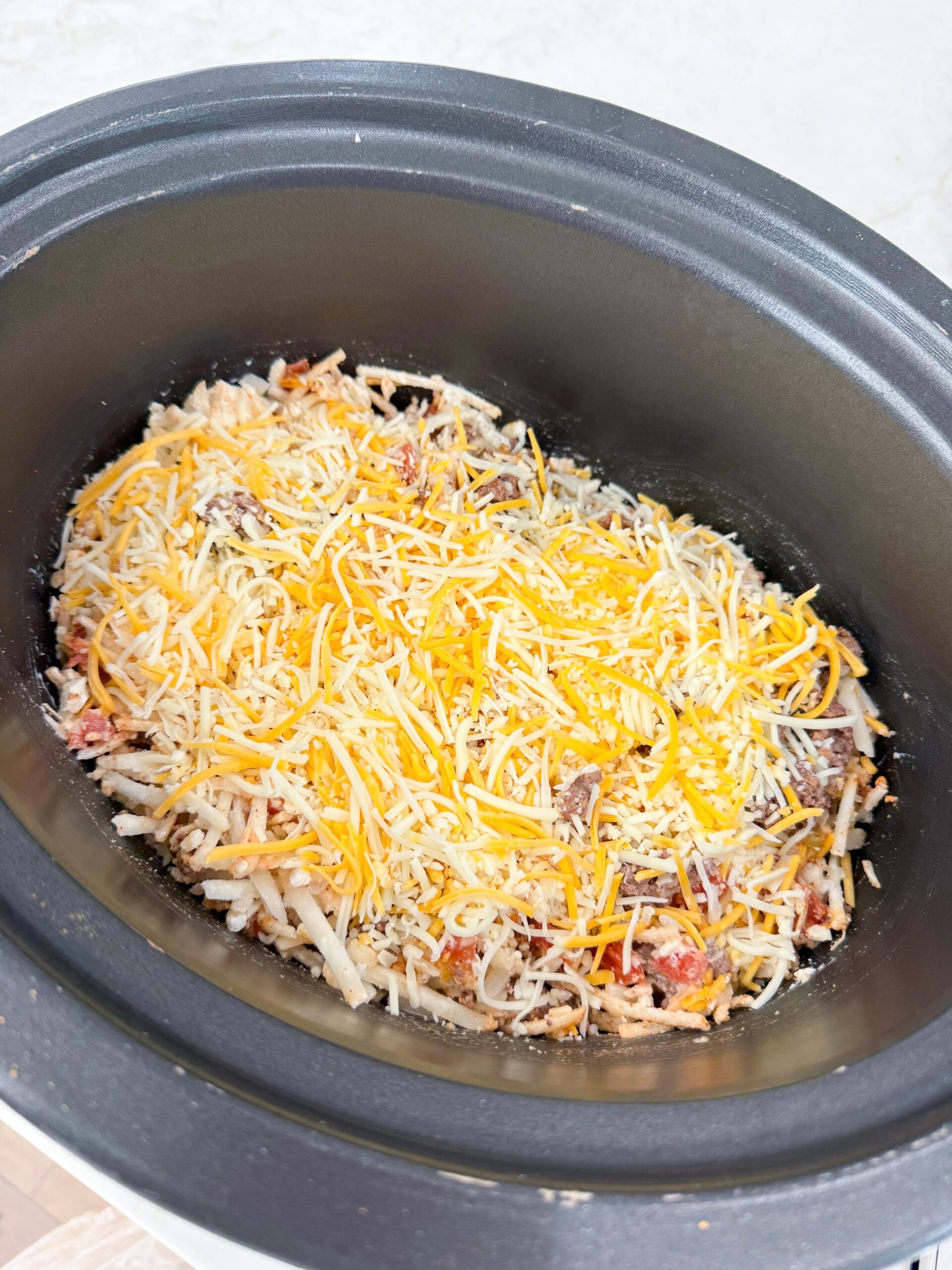 cooked ground beef, frozen hash browns, cheese, Rotel, garlic, heavy cream, and taco seasoning in a slow cooker