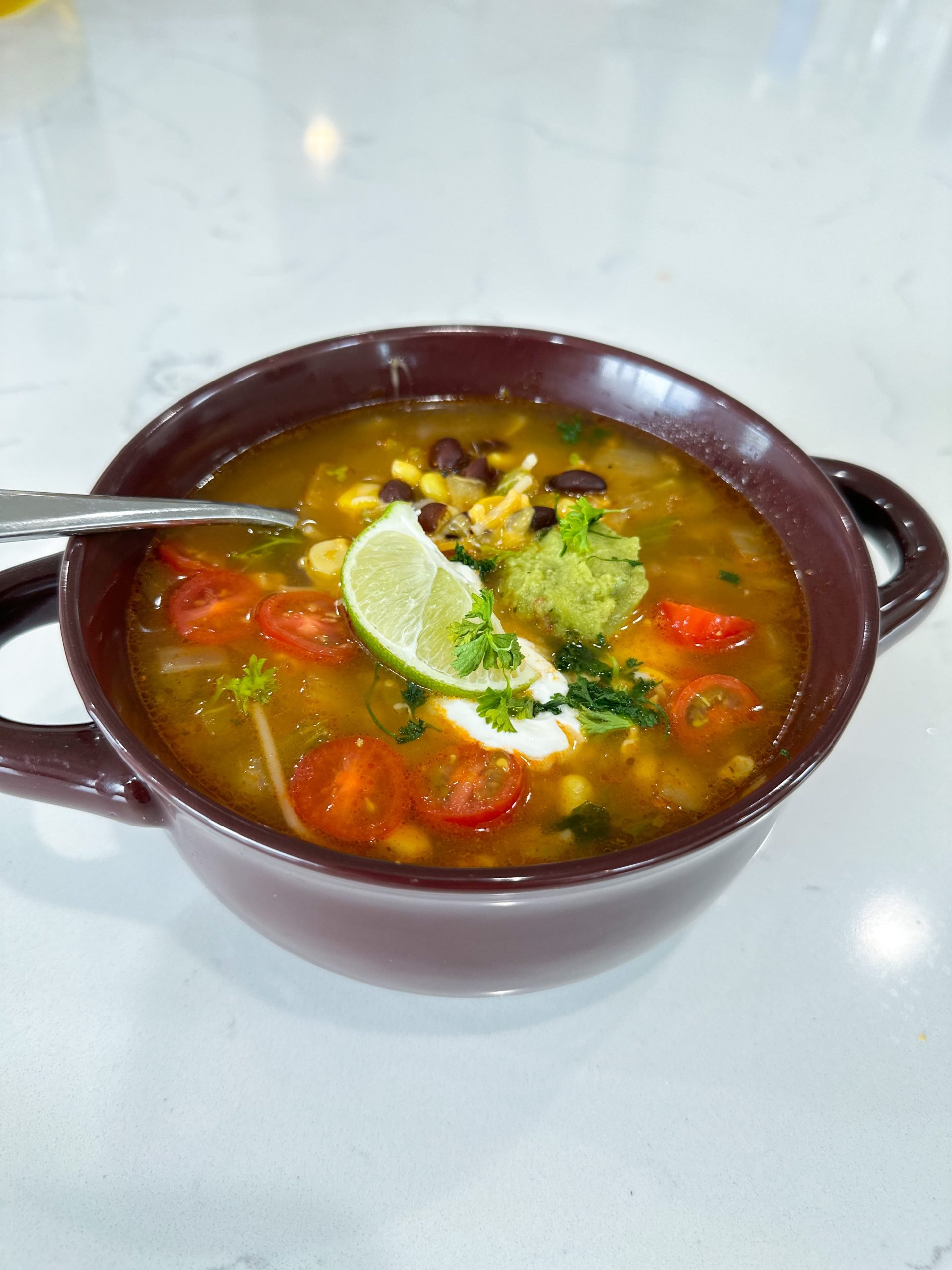 Bowl of Spanish rice soup with beans, corn, and tomatoes in tomato broth