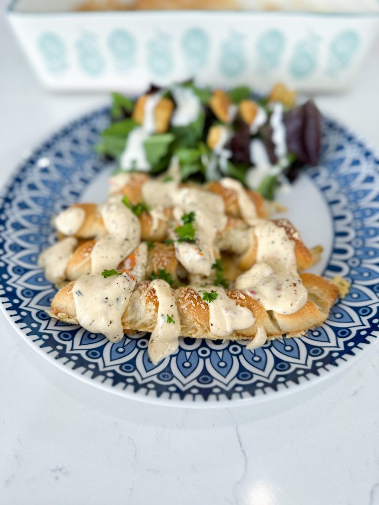 Golden baked chicken wrapped in crescent dough, drizzled with creamy sun-dried tomato sauce