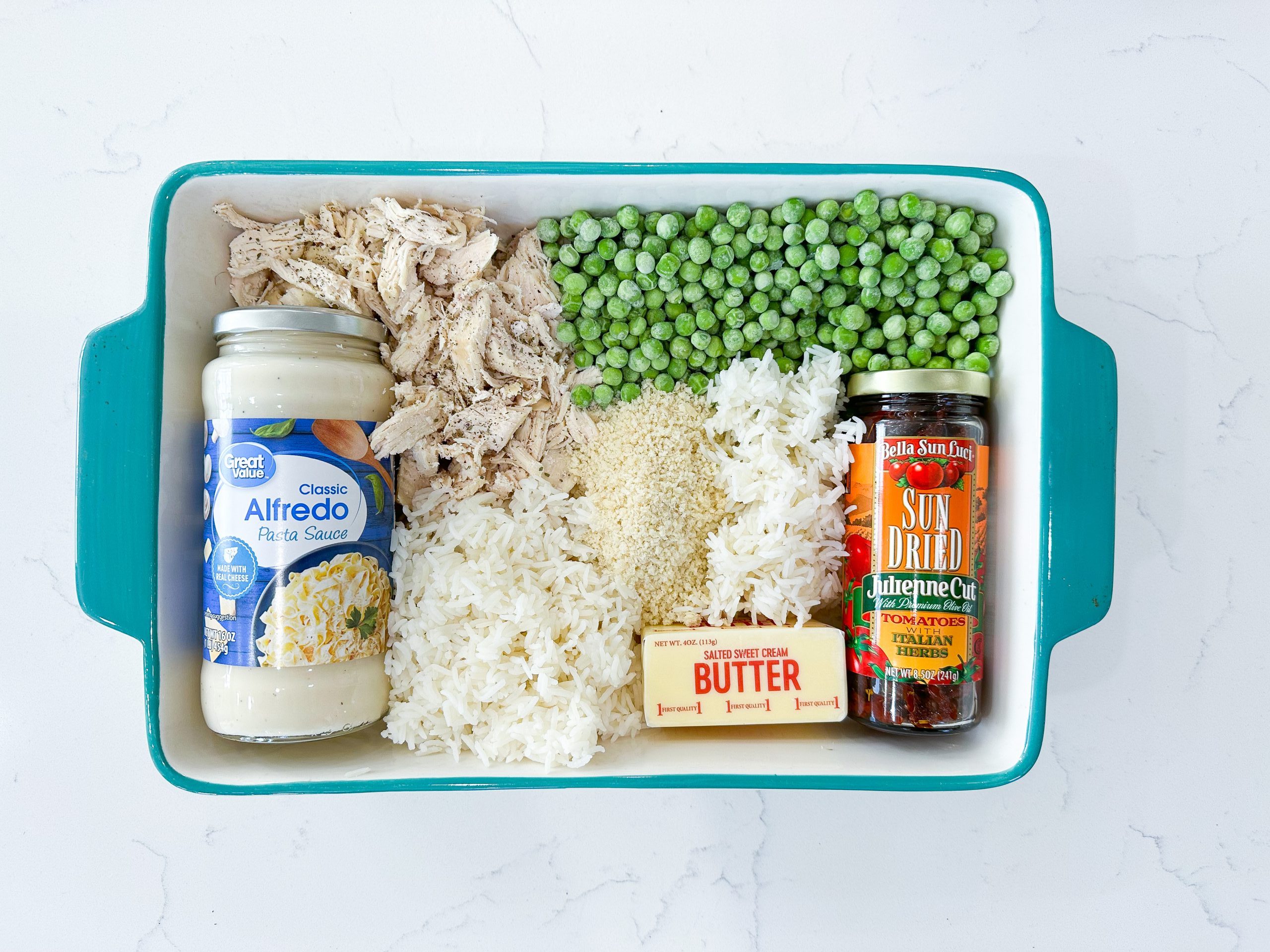rice, chicken, Alfredo sauce, peas, and breadcrumbs on a counter