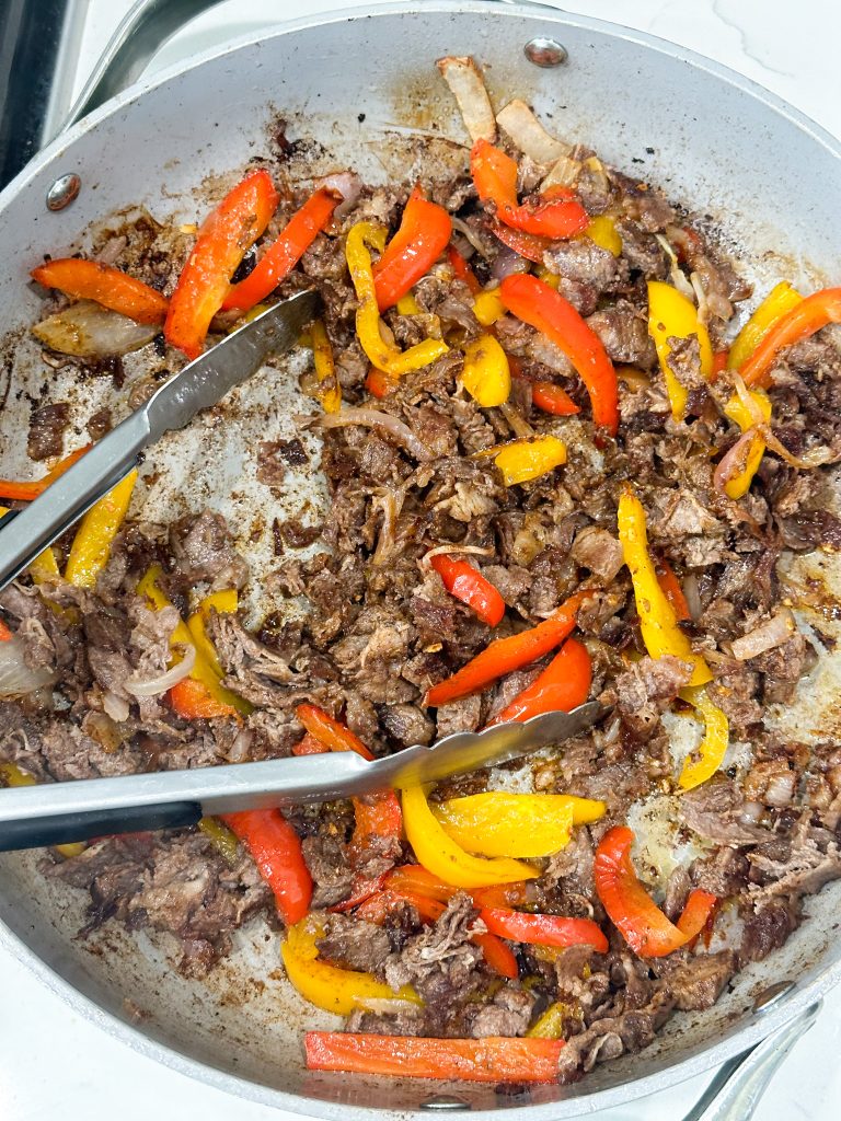 steak and peppers cooking in a skillet