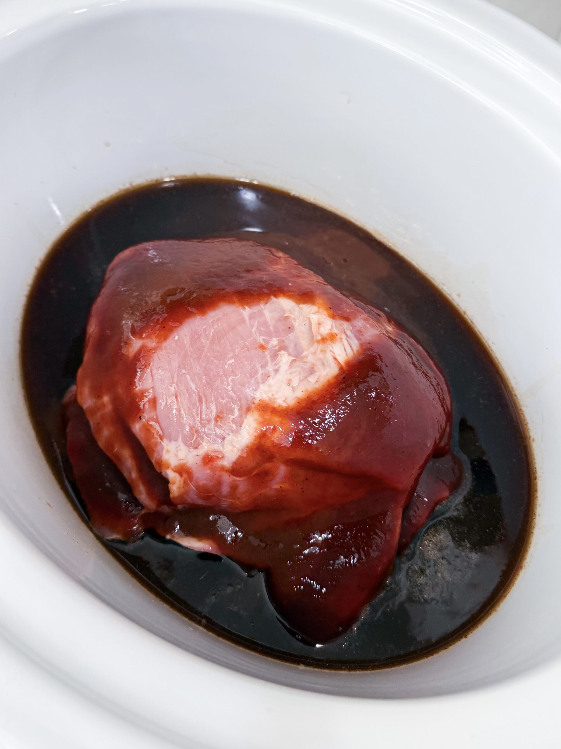 Dr Pepper soda poured over pork loin and barbecue sauce in a slow cooker