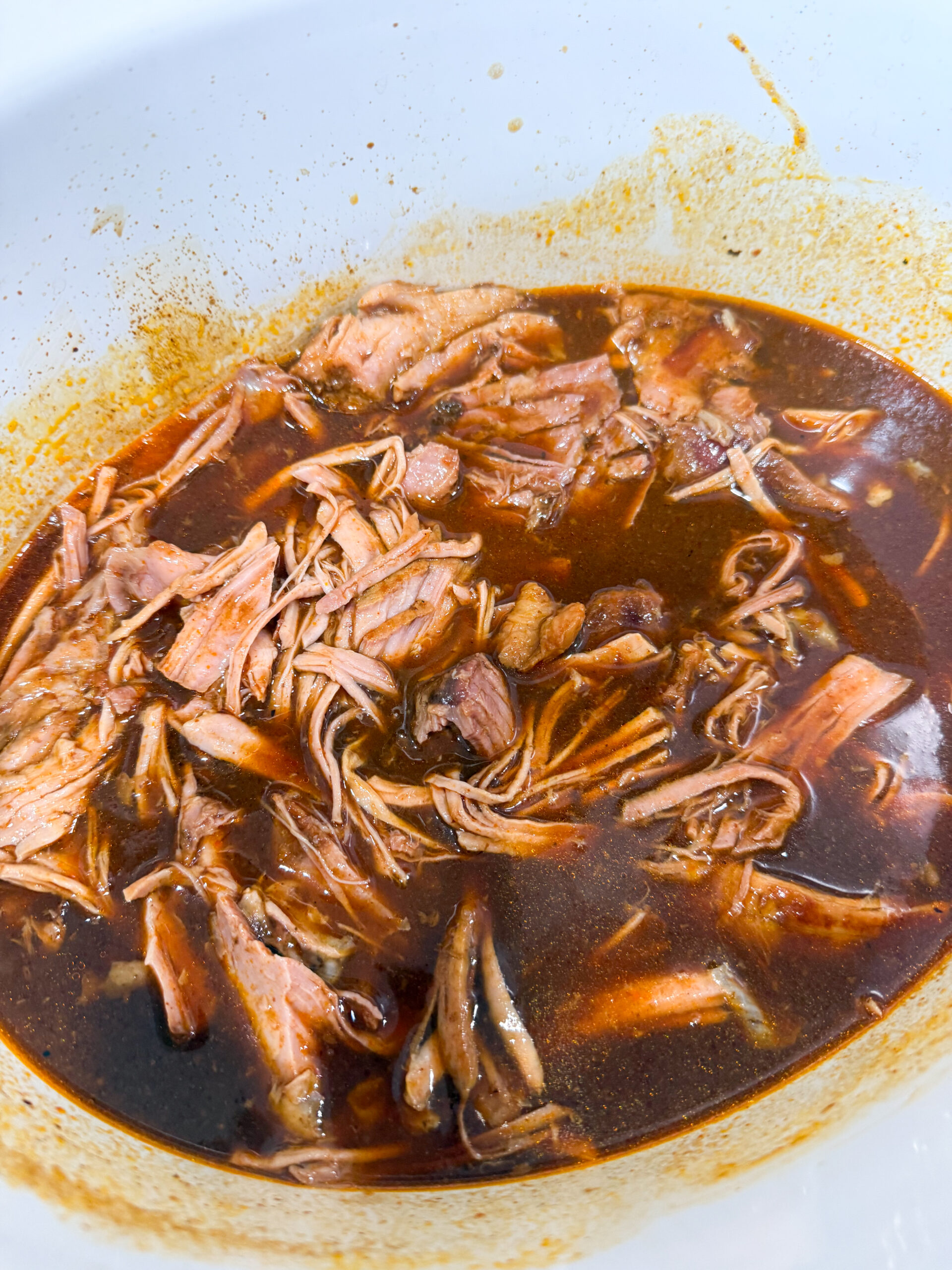 shredded barbecue pork in a slow cooker with juices