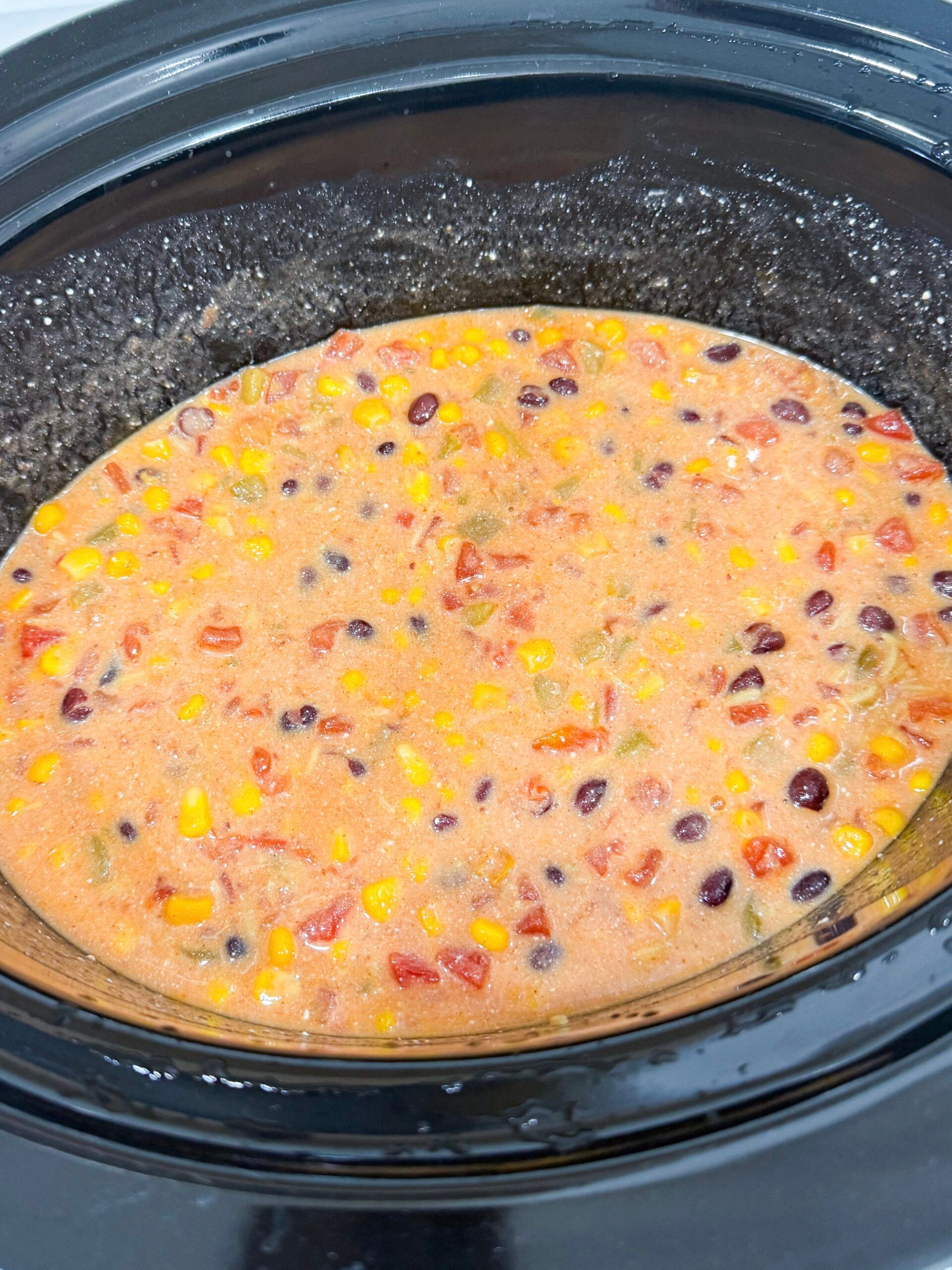 corn, black beans, diced tomatoes, enchilada sauce, green chilis, broth, and cream cheese in a slow cooker