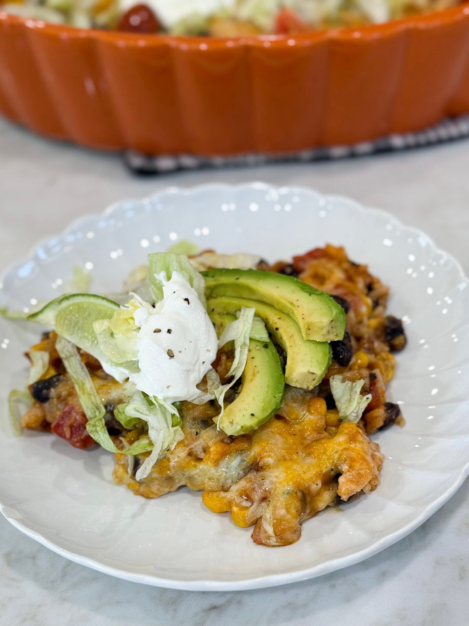 Fiesta chicken casserole on plate topped with melted cheese and fresh toppings