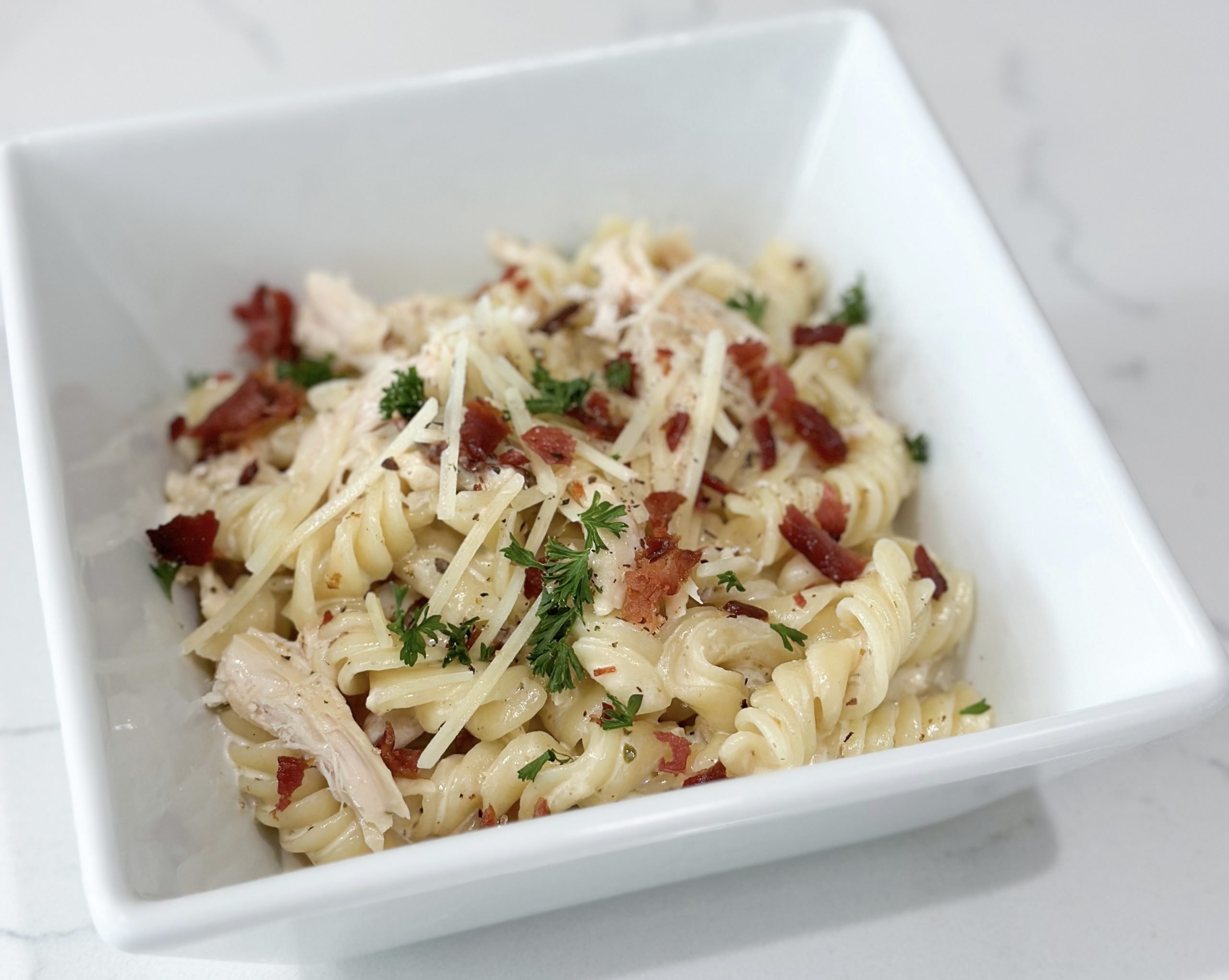 creamy rotini pasta with chicken and bacon in a serving dish