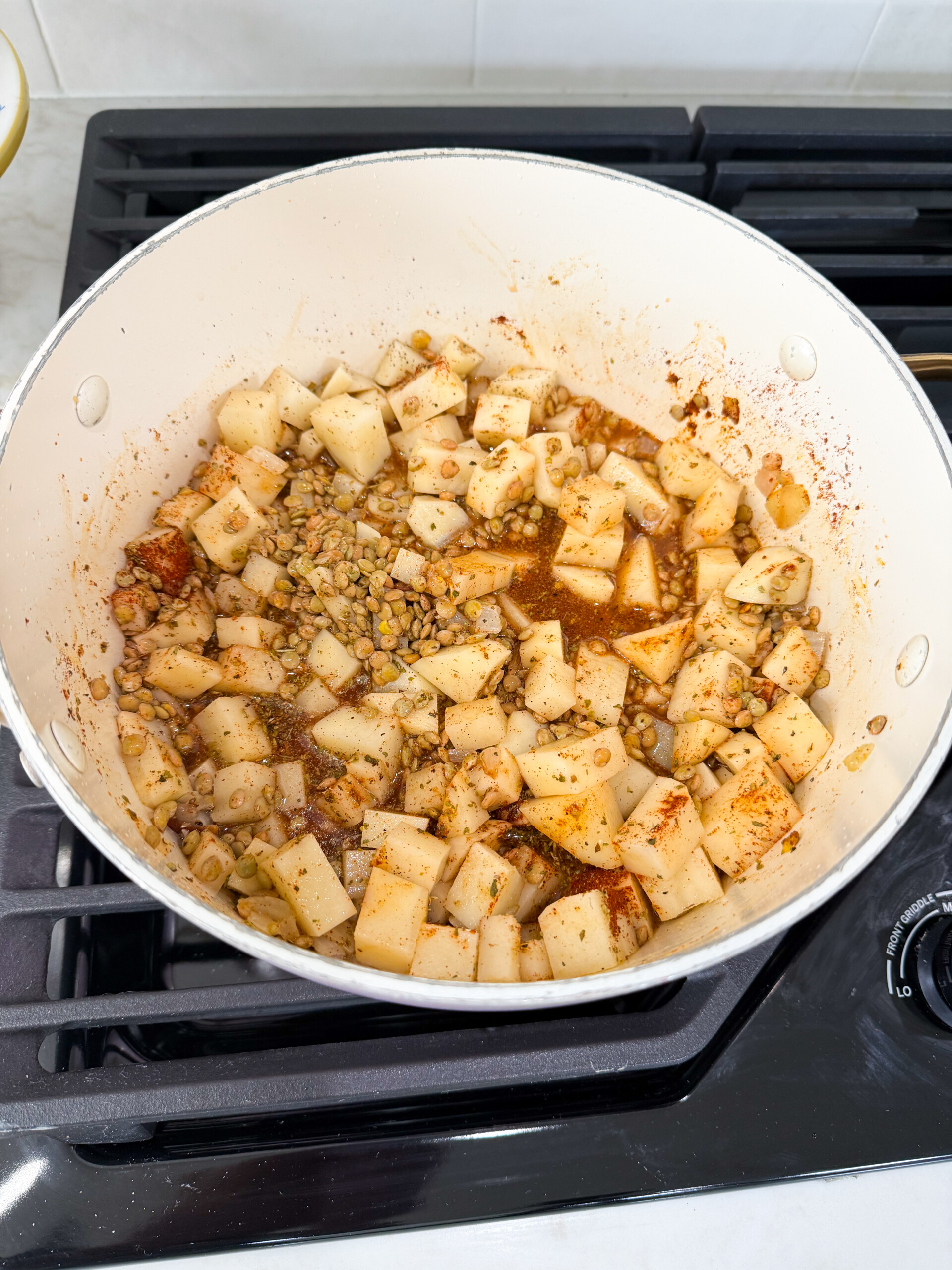 Cooked lentils and potatoes in a pot.