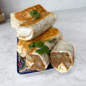 Lentil burritos stacked up on a plate.