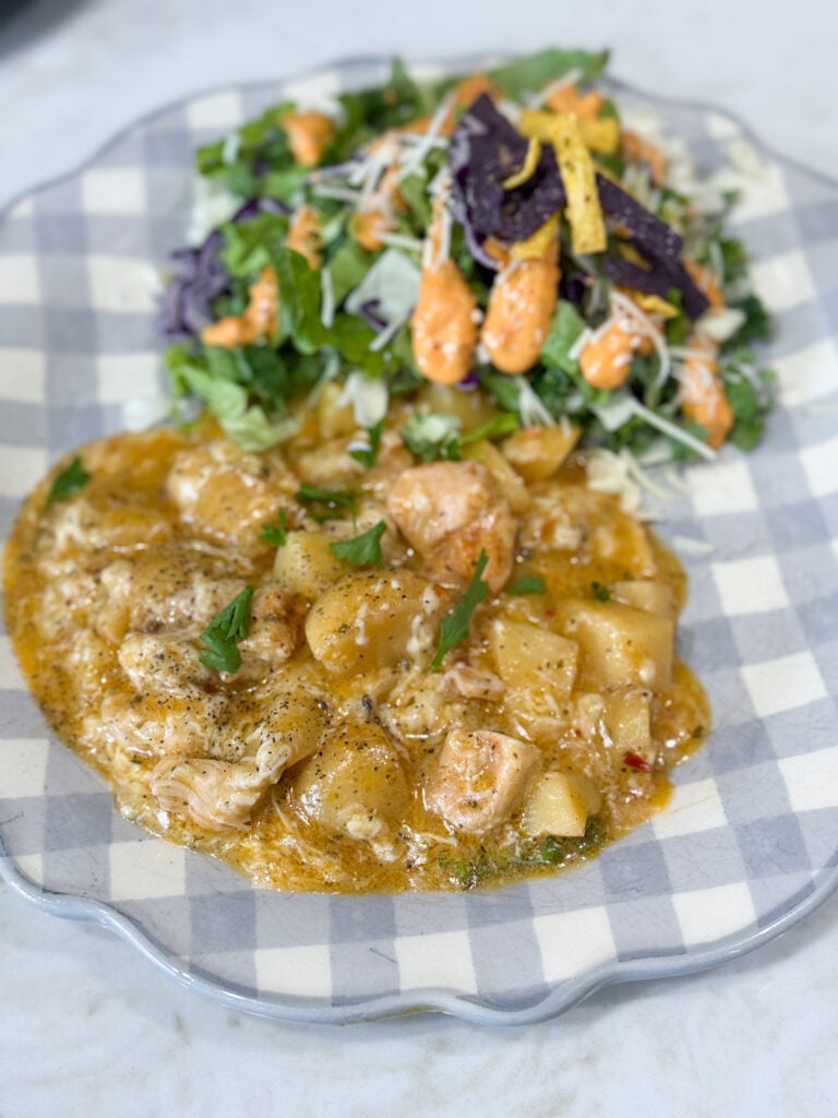 chicken and potatoes on a blue and white plate with salad
