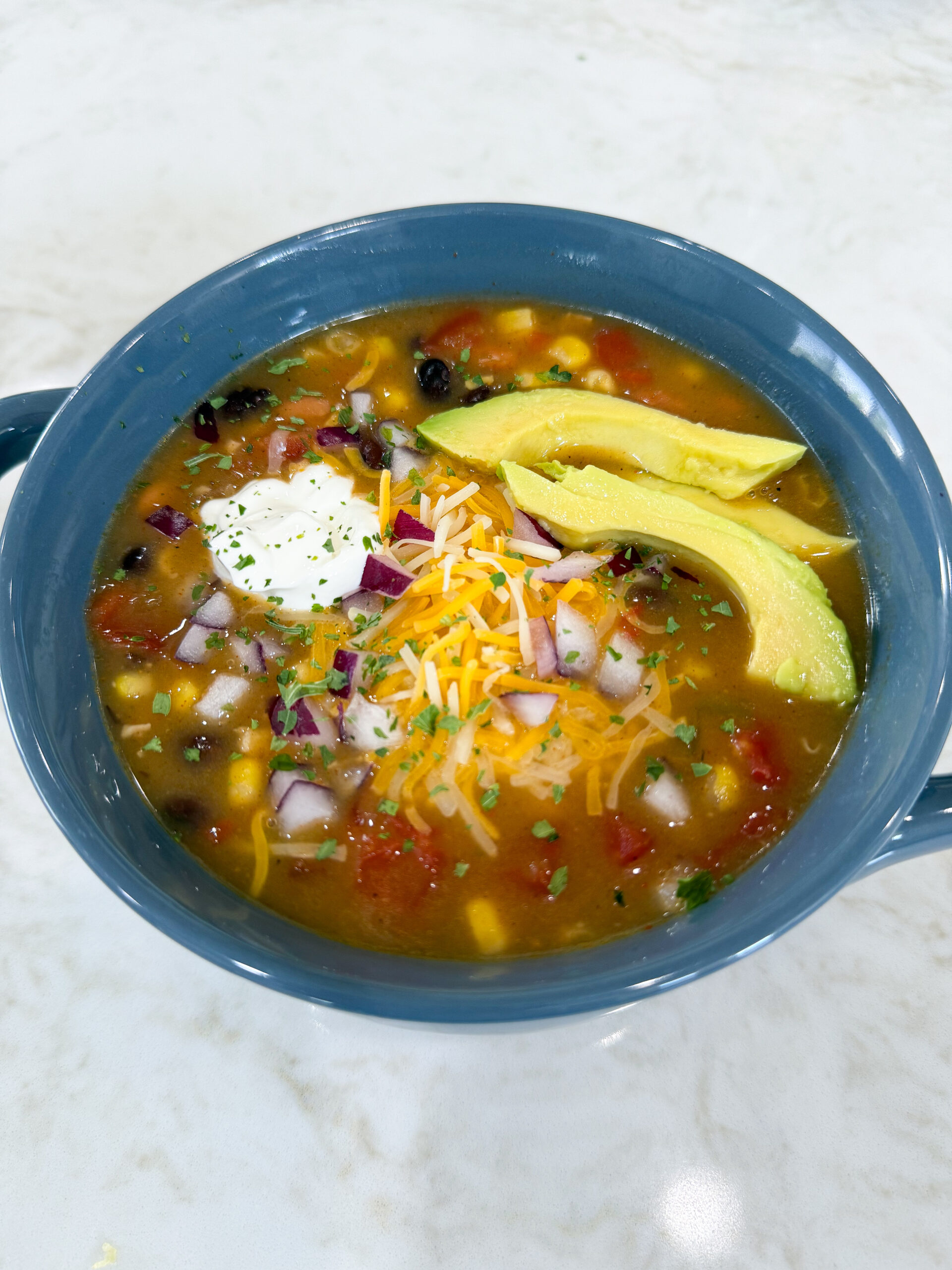 Bowl of 8 Can Chicken Taco Soup with beans, corn, and chicken topped with sour cream and cheese