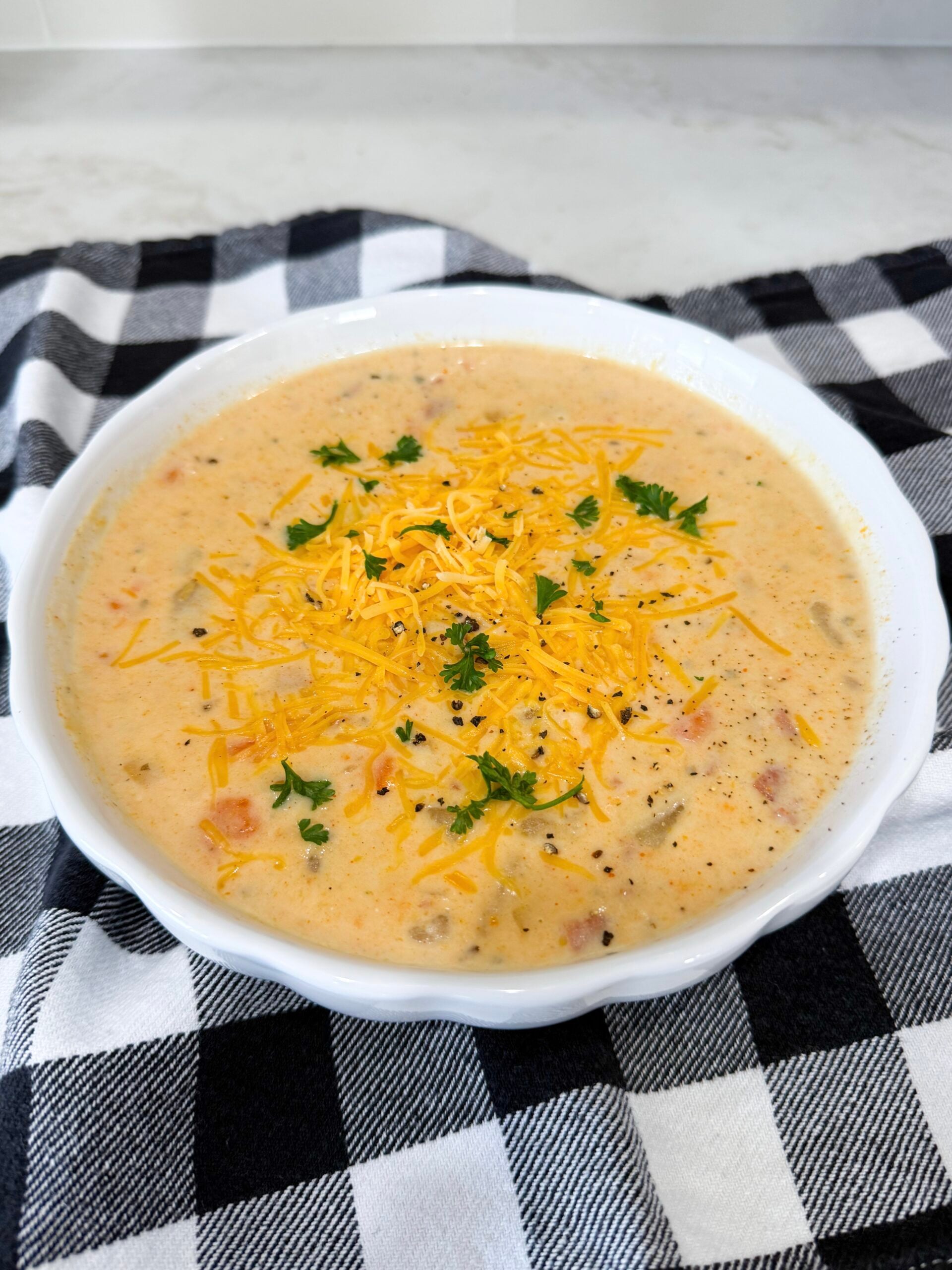 Bowl of Slow Cooker Ham and Potato Soup with carrots, potatoes, and cheddar cheese