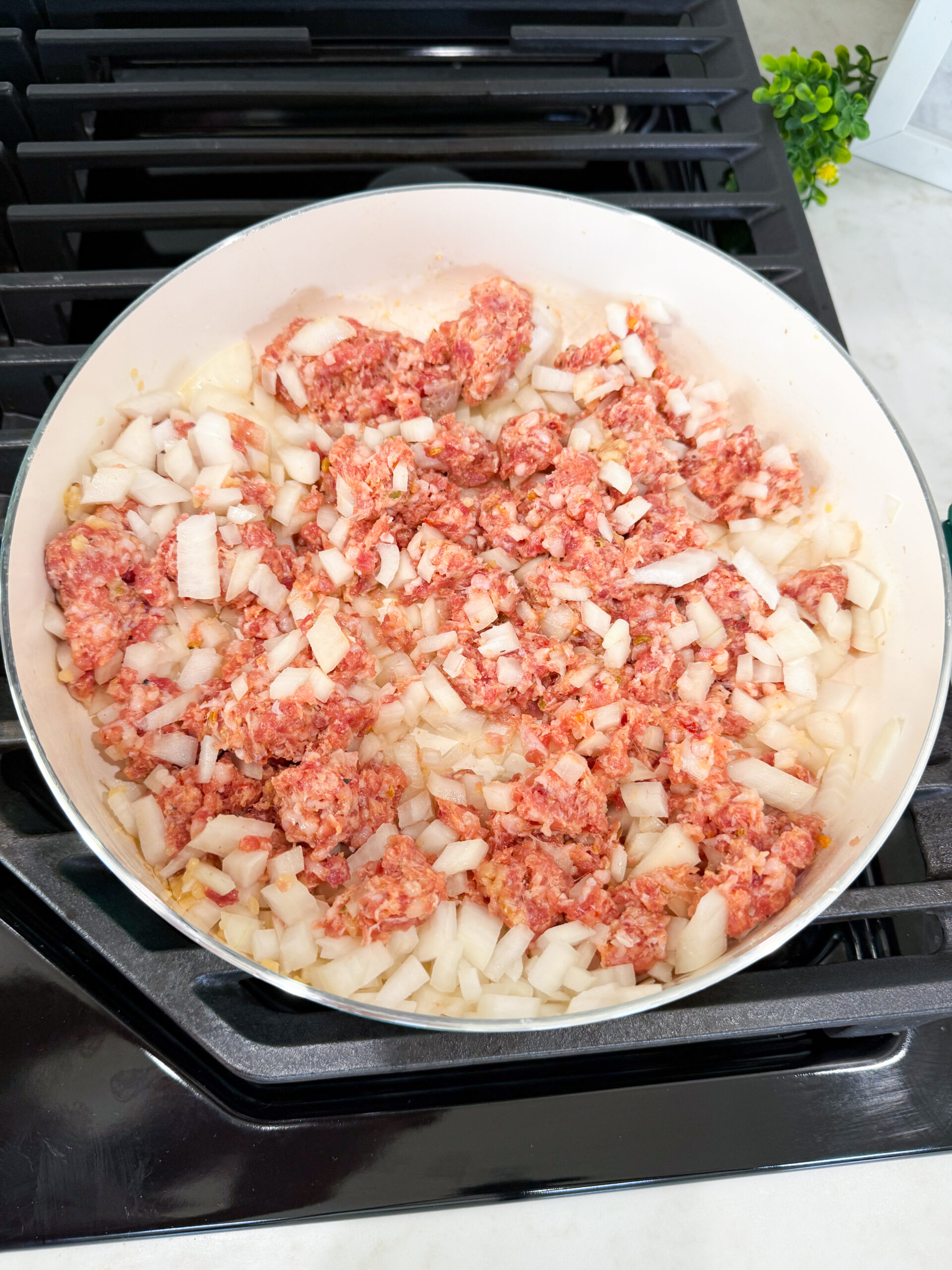 Ground Italian sausage and diced onions cooking together in a skillet for Million Dollar Spaghetti.