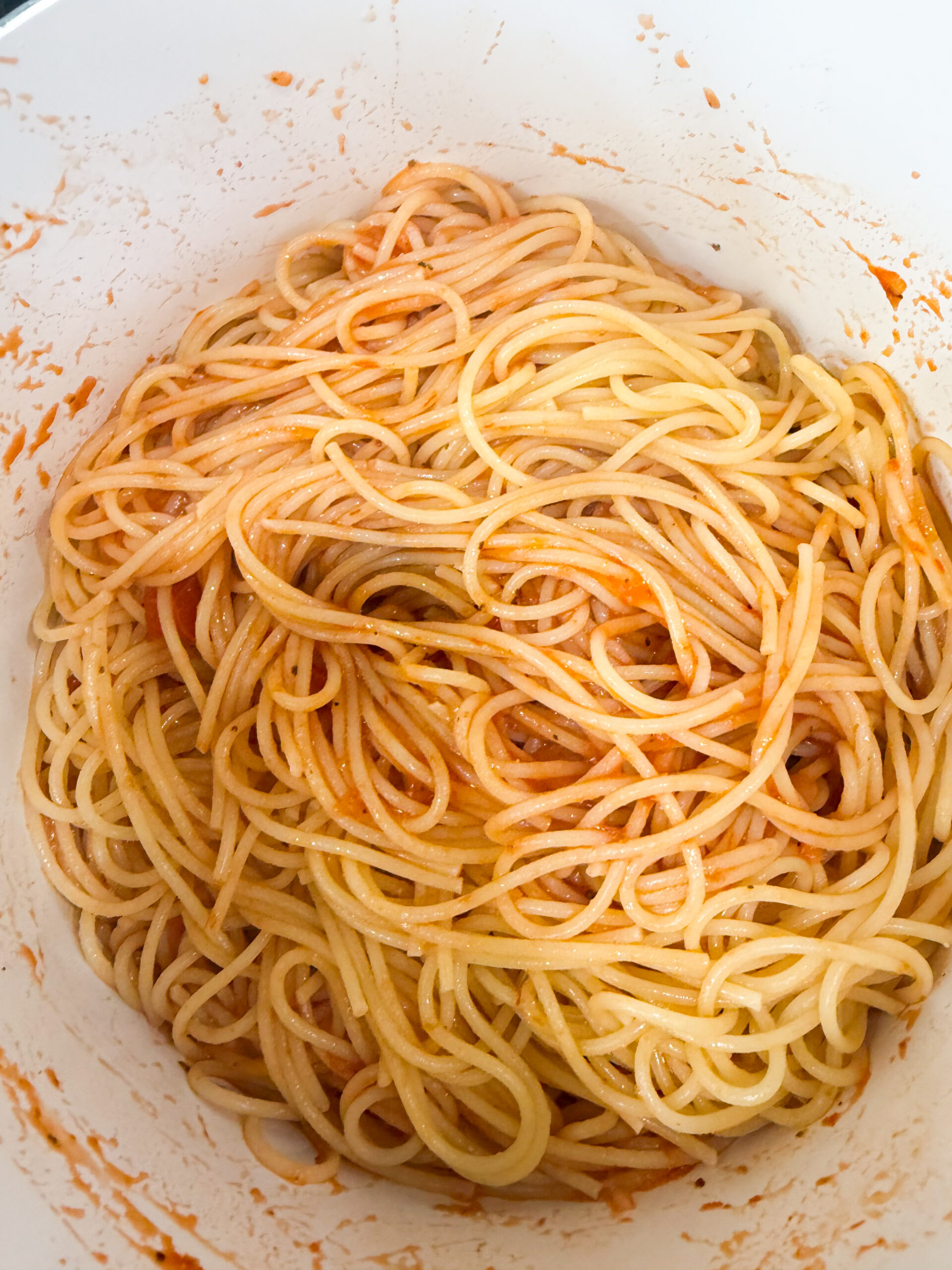 Cooked spaghetti tossed with marinara sauce in a large pot.