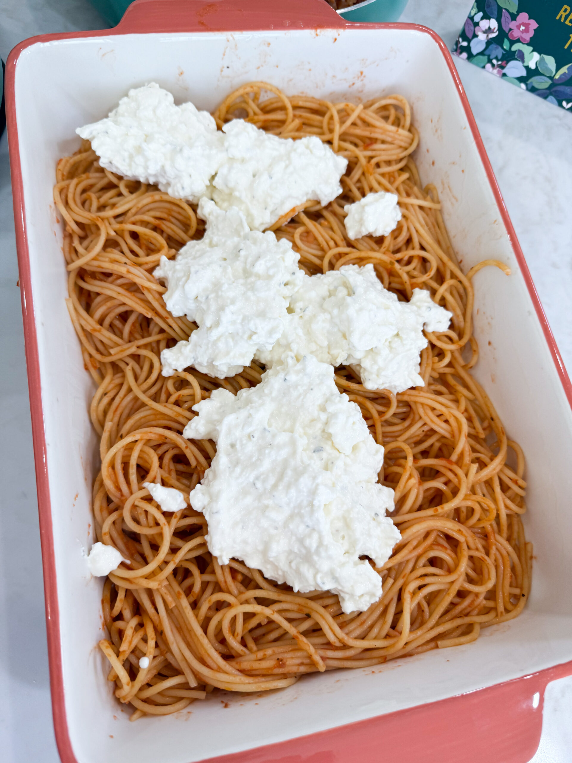 Ricotta and cream cheese mixture spread over spaghetti in the casserole dish.