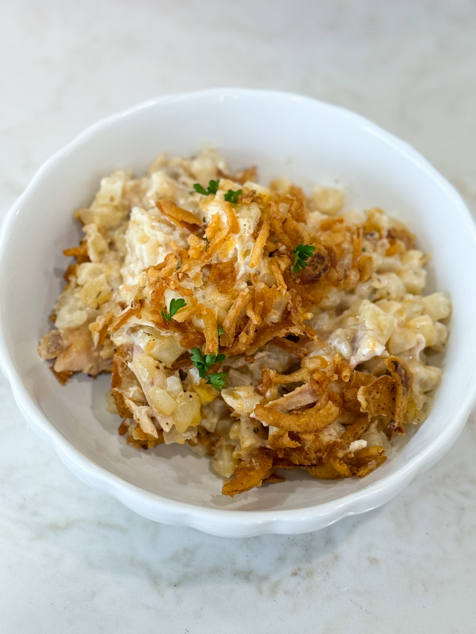Serving of Onion Chicken Potato Casserole on a plate with chicken, potatoes, and crispy onion topping.