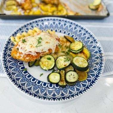 Sheet pan chicken topped with marinara and melted mozzarella with roasted zucchini and squash