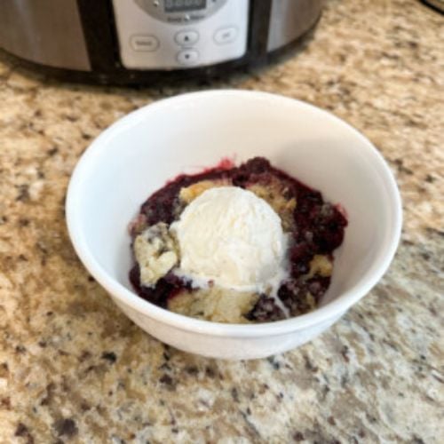 Slow Cooker Berry Cobbler topped with vanilla ice cream in a bowl