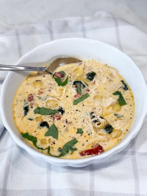 Bowl of creamy Slow Cooker Marry Me Chicken Soup with pasta, spinach, and sun-dried tomatoes