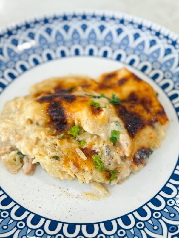 Serving of Spinach Chicken Orzo Casserole on a plate with creamy orzo, spinach, and melted cheese.
