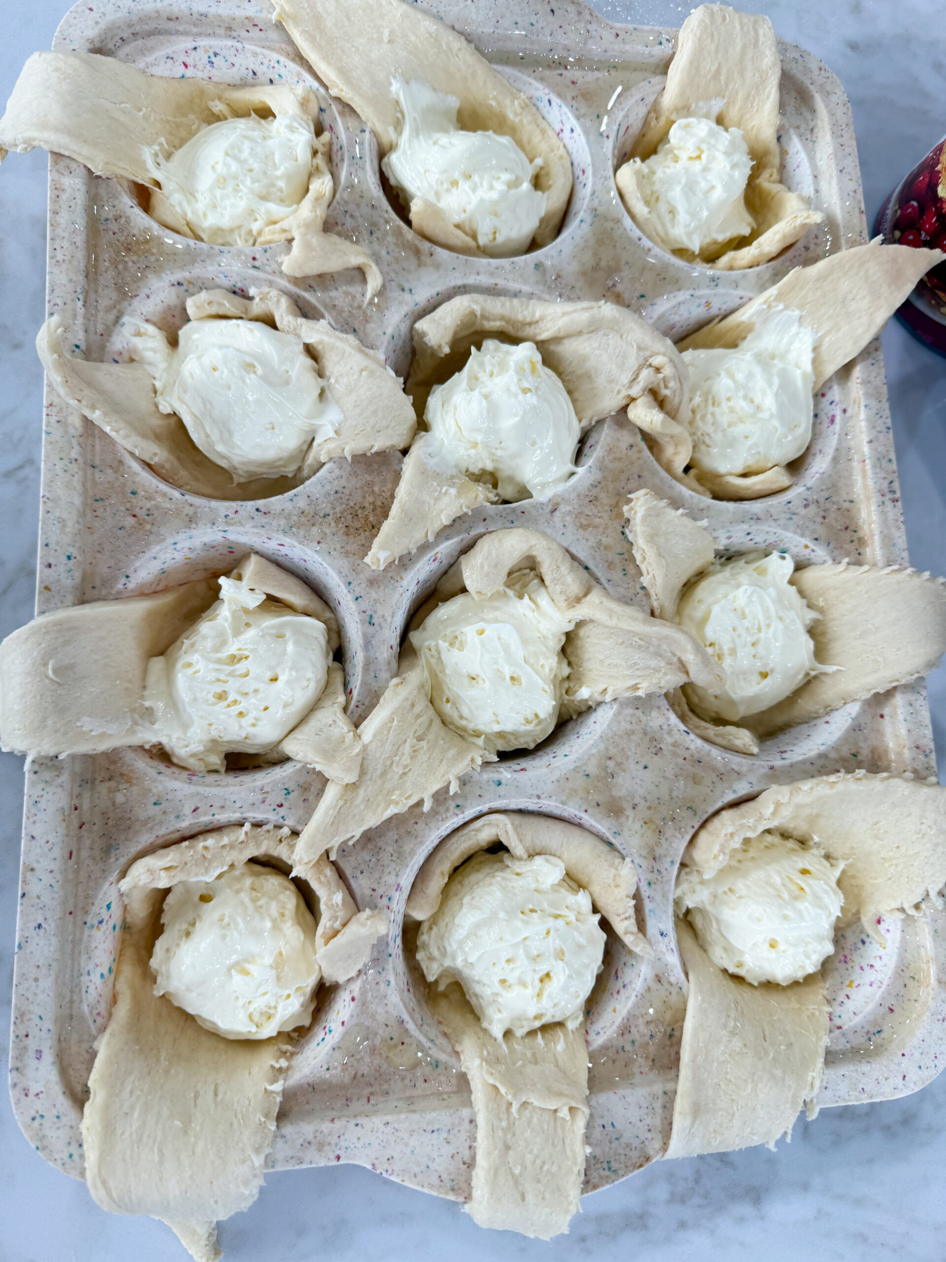 Filling dough cups with cheesecake.