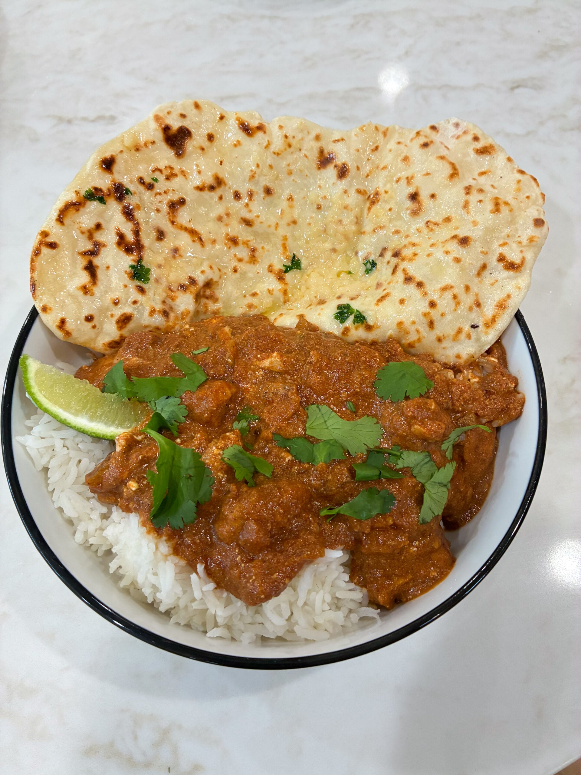 butter chicken plated with naan bread and rice