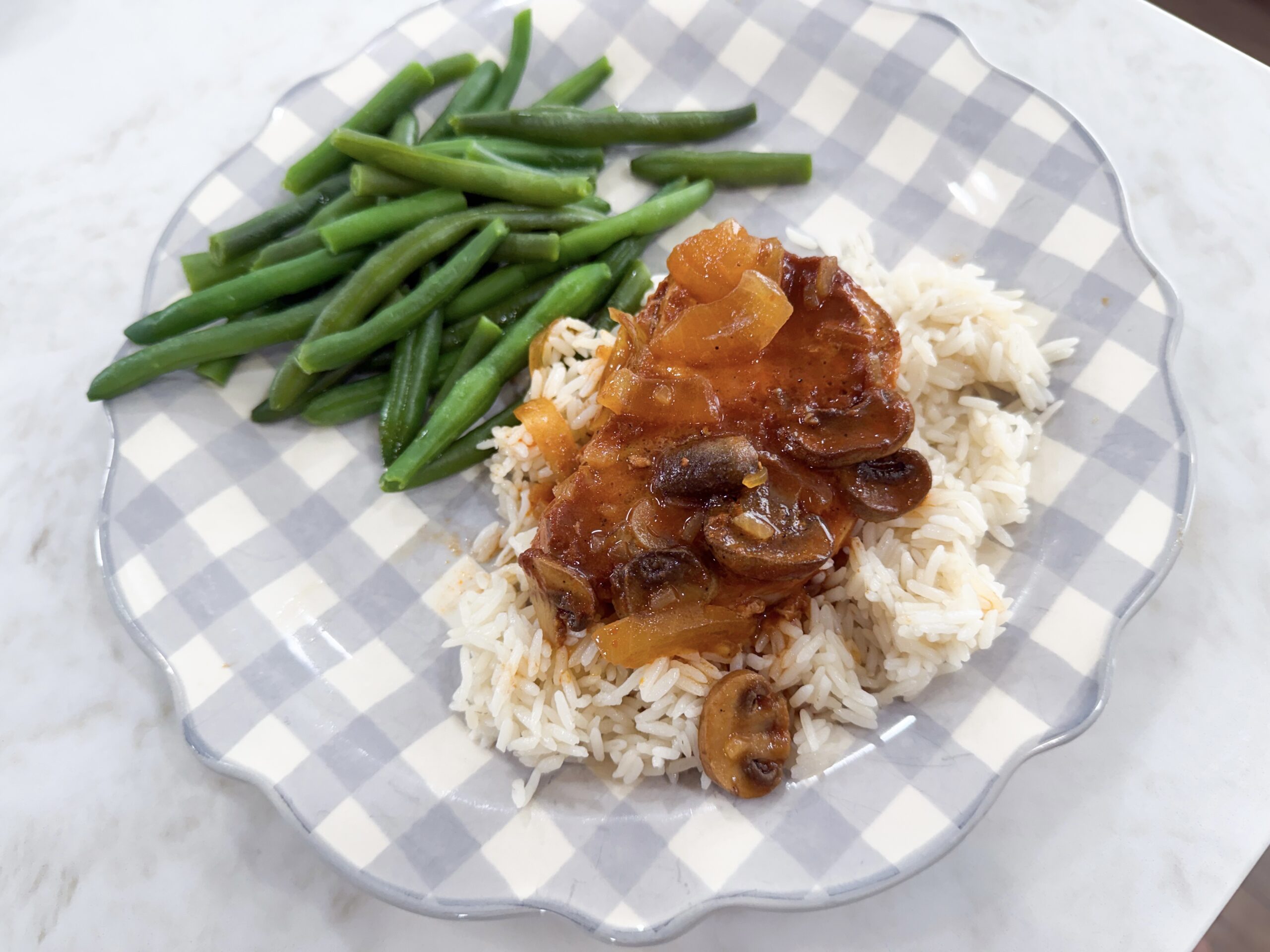 slow cooker smothered pork chops with onion mushroom gravy served over mashed potatoes with green beans